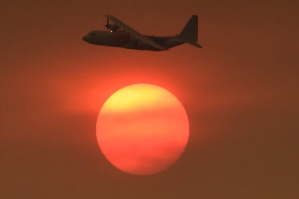 
              In this photo provided by the Santa Barbara County Fire Department, with smoke obscuring the sun in the distance, a Coulson C-130 Air Tanker turns in to make a drop on a hillside near Toro Canyon Road in Carpinteria, Calif., Monday, Dec. 11, 2017. Ash fell like snow and heavy smoke had residents gasping for air Monday as a wildfire exploded in size, becoming the fifth largest in state history. (Mike Eliason/Santa Barbara County Fire Department via AP)
            