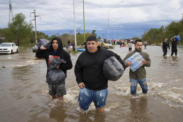 Residents wade through flooded streets following heavy rains in Campana, Argentina, Saturday, May 17, 2025. (AP Photo/Rodrigo Abd)