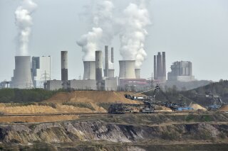 FILE - In this April 3, 2014 file photo giant machines dig for brown coal at the open-cast mining Garzweiler in front of a smoking power plant near the city of Grevenbroich in western Germany. World leaders breathed an audible sigh of relief that the United States under President Joe Biden is rejoining the global effort to curb climate change, a cause that his predecessor had shunned. (AP Photo/Martin Meissner, File)