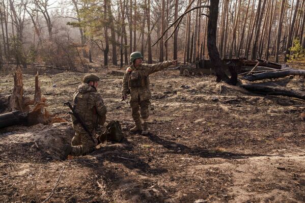 Andrii Serhieiev, right, a soldier with Ukraine's 53rd Brigade who lost a leg in combat, and another soldier install explosives near the front line in Ukraine's Donetsk region on Feb. 13, 2025. (AP Photo/Evgeniy Maloletka)
