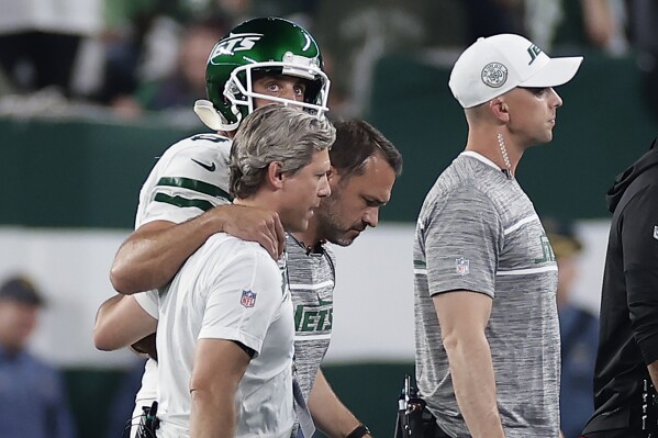 New York Jets quarterback Aaron Rodgers (8) is helped off the field during the first quarter of an NFL football game against the Buffalo Bills, Monday, Sept. 11, 2023, in East Rutherford, N.J. (AP Photo/Adam Hunger)