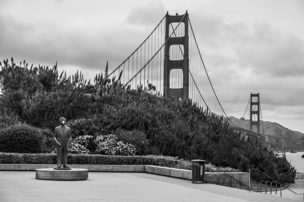A mask covers the mouth on the statue of Golden Gate Bridge chief engineer Joseph Strauss at an empty visitors plaza in San Francisco on April 17, 2020. Normally, the months leading into summer bring bustling crowds to the city's famous landmarks, but this year, because of the coronavirus threat they sit empty and quiet. Some parts are like eerie ghost towns or stark scenes from a science fiction movie. (AP Photo/Eric Risberg)