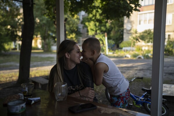 Valeria Pototska cuddles her 5-year-old son David outside their house in Kupiansk-Vuzlovyi, Ukraine, Wednesday, Aug. 23, 2023. \(AP Photo/Bram Janssen)