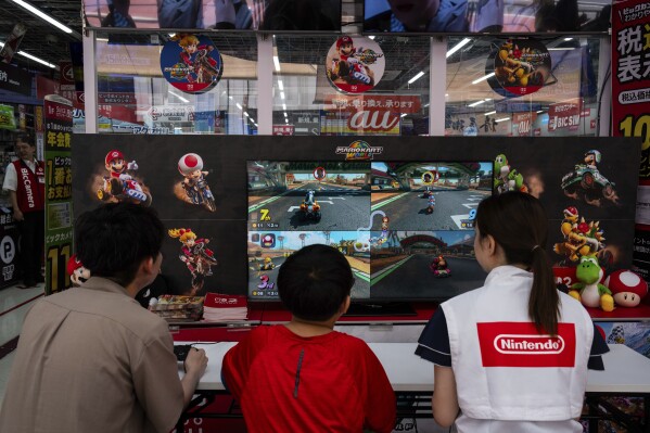 Staff and members of the public try the Nintendo Switch 2 during a launch event at an electronics retailer in Tokyo, Thursday, June 5, 2025. (AP Photo/Louise Delmotte)