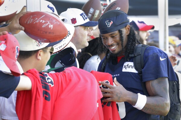 Houston Texans wide receiver John Metchie III gives autographs to fans after the NFL football team's training camp Sunday, July 30, 2023, in Houston. (AP Photo/Michael Wyke)