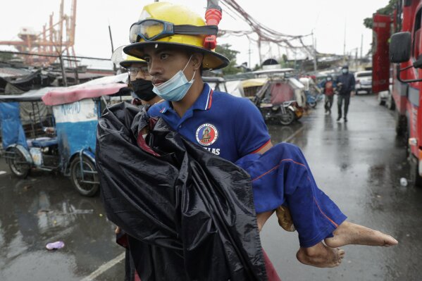 A rescuer carries a sick child as they evacuate residents living along a coastal community in Manila, Philippines on Sunday, Nov. 1, 2020. A super typhoon slammed into the eastern Philippines with ...