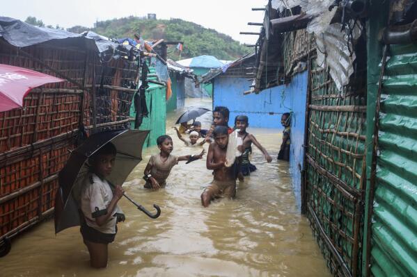 Rohingya refugee children play in flood waters at the Rohingya refugee camp in Kutupalong, Bangladesh, Wednesday, July 28, 2021. Days of heavy rains have brought thousands of shelters in various Rohingya refugee camps in Southern Bangladesh under water, rendering thousands of refugees homeless. (AP Photo/ Shafiqur Rahman)