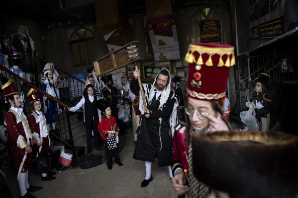 FILE - Jewish ultra-Orthodox men and children, some wearing costumes, celebrate the festival of Purim at a synagogue in Bnei Brak, Israel, March 17, 2022. Purim celebrates the biblical story of how a plot to exterminate Jews in Persia was thwarted, and thus is embraced as an affirmation of Jewish survival throughout history. For many Jews, it will have extra significance in 2024 during a war in Gaza triggered by the Oct. 7, 2023, attacks on Israel in which Hamas killed 1,200 people and took about 250 others hostage. (AP Photo/Oded Balilty, File)