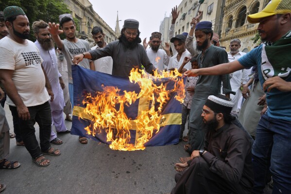 FILE - Supporters of a radical Islamist party 'Tehreek-e-Labaik Pakistan' burn the representation of Swedish flag during a rally to denounce burning of Islam's holy book 'Quran', in Karachi, Pakistan, on July 7, 2023. A senior Swedish official said Monday Aug. 14, 2023 Swedes abroad and businesses linked to Sweden“should observe increased vigilance and caution,” following recent Quran burnings in the country and protests in the Muslim world. (AP Photo/Fareed Khan, File)