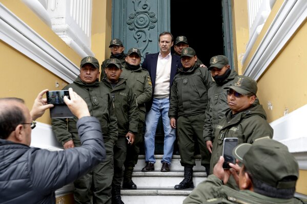Former Bolivian President Jose Fernando Quiroga poses with police guarding Congress in La Paz, Bolivia, Monday, Nov. 11, 2019. Former President Evo Morales' Nov. 10 resignation, under mounting pressure from the military and the public after his re-election victory triggered weeks of fraud allegations and deadly demonstrations, leaves a power vacuum and a country torn by protests against and for his government. (AP Photo/Natacha Pisarenko)