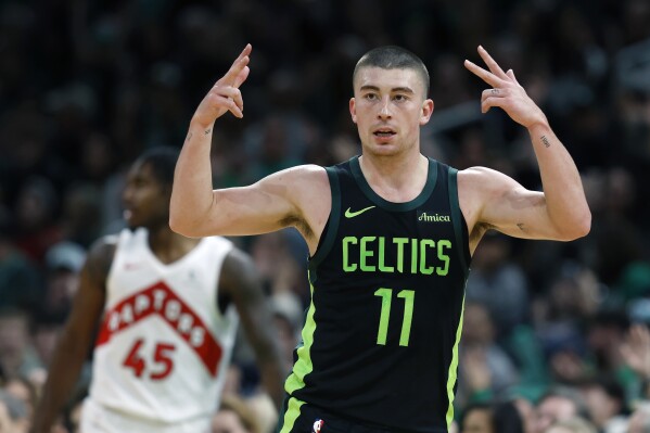 Boston Celtics' Payton Pritchard (11) celebrates his three-pointer in front of Toronto Raptors' Davion Mitchell (45) during the first half of an NBA basketball game, Tuesday, Dec. 31, 2024, in Boston. (AP Photo/Michael Dwyer)
