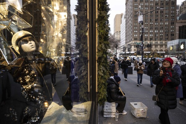 Passersby look at store window displays on the 5th Avenue, Monday, Dec. 11, 2023, in New York. On Thursday, the Commerce Department releases U.S. retail sales data for November. (AP Photo/Yuki Iwamura)