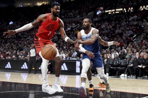 Minnesota Timberwolves guard Mike Conley, right, passes the ball as Portland Trail Blazers center Deandre Ayton defends during the second half of an NBA basketball game in Portland, Ore., Tuesday Feb. 13, 2024. (APPhoto/Steve Dykes)