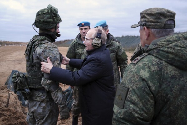 FILE - Russian President Vladimir Putin, center, speaks to a soldier while visiting a military training center of the Western Military District in the Ryazan region of Russia as Defense Minister Sergei Shoigu, right, stands nearby, on Thursday, Oct. 20, 2022. With the fighting in Ukraine now in its third year, Putin hopes to achieve his goals by biding his time and waiting for Western support for Ukraine to wither while Moscow maintains its steady military pressure along the front line. (Mikhail Klimentyev, Sputnik, Kemlin Pool Photo via AP, File)