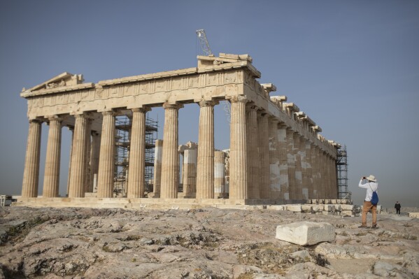 A man takes a picture next the ancient Parthenon temple at the Acropolis hill of Athens, on Monday, May 18, 2020. (AP Photo/Petros Giannakouris)