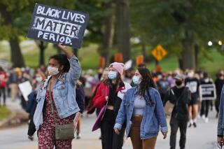 A woman holds up a sign during q protest, Tuesday, Sept. 29, 2020, in Cleveland.  Racism would be declared a public health crisis in Ohio and the day celebrating the official end of slavery would become a paid state holiday under racial justice measures reintroduced Tuesday, Feb. 23, 2021, after unsuccessful efforts to pass them during the last legislative session. (AP Photo/Tony Dejak, File)