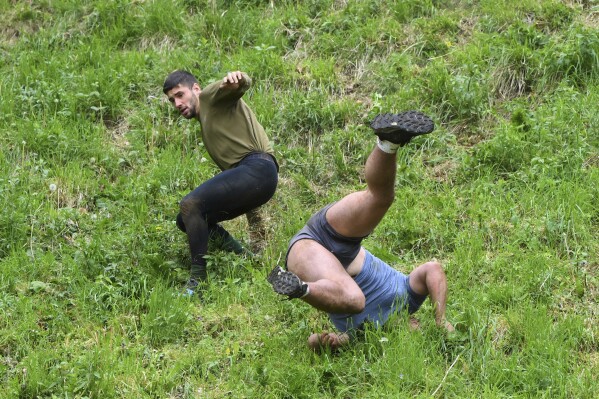 Participants compete in the men's downhill race category of the traditional annual Cheese Rolling contest at Cooper's Hill in Brockworth, Gloucestershire, England, Monday, May 26, 2025.(AP Photo/Anthony Upton)