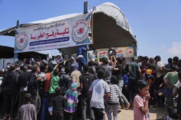 Palestinians struggle to get donated food at a community kitchen in Khan Younis, Gaza Strip, Monday, May 5, 2025. (AP Photo/Abdel Kareem Hana)