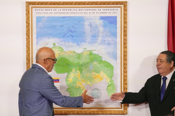 National Assembly Speaker Jorge Rodriguez, left, and Chairman of the Special Commission for the Defense of Guyana Essequibo Hermann Escara, shake hands after unveiling the new map of Venezuela which includes the territory of Essequibo, a strip of land administered and controlled by Guyana but claimed by Venezuela, in Caracas, Venezuela, Friday, December 8, 2023. (AP Photo/Matias Delacroix)
