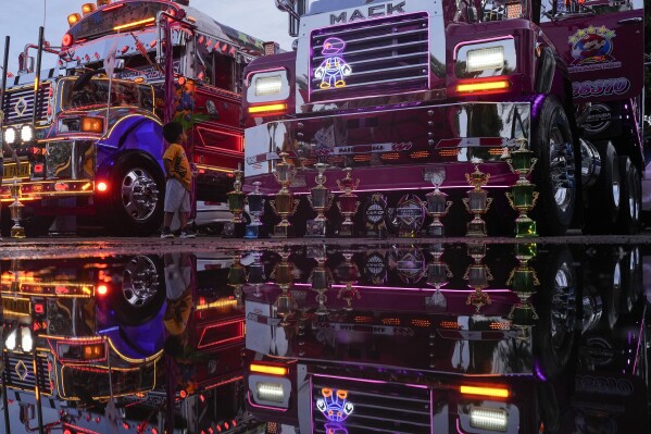 A boy watches buses during a Red Devils tuning exhibition in La Chorrera, Panama, Sunday, June 30, 2024. The Red Devils are repurposed U.S. school buses once used in the Panama Canal Zone and later as public transport, now adapted for private and cultural use. (AP Photo/Matias Delacroix)