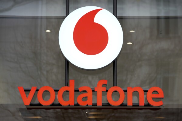FILE - The logo of the mobile service provider 'vodafone' is pictured on the entrance of a company's store at the Kurfuerstendamm shopping boulevard in Berlin, Germany, Tuesday, Feb. 1, 2022. British cellphone company Vodafone confirmed Friday, March 15, 2024, that it is selling its Italian business to Switzerland’s Swisscom for 8 billion euros ($8.7 billion) and will hand back half of the proceeds to its shareholders through the buyback of company shares. (AP Photo/Michael Sohn, File)