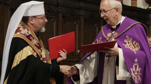 Archbishop Sviatoslav Shevchuk of the Ukrainian Greek Catholic Church, left, and the head of Poland's Roman Catholic Church, Archbishop Stanislaw Gadecki, right, exchange forgiveness and reconciliation notes during a joint religious service held as part of observances honoring some 100,000 Poles murdered by Ukrainian nationalists in 1943-44, at St. John's cathedral in Warsaw, Poland, on Friday, July 7, 2023. (AP Photo/Czarek Sokolowski)
