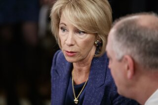 
              Education Secretary Betsy DeVos, talks with Louisiana Gov. John Bel Edwards before President Donald Trump arrives to speak at the 2019 White House Business Session with Our Nation's Governors in the State Dining Room of the White House in Washington, Monday, Feb. 25, 2019. (AP Photo/Carolyn Kaster)
            