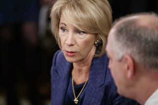 Education Secretary Betsy DeVos, talks with Louisiana Gov. John Bel Edwards before President Donald Trump arrives to speak at the 2019 White House Business Session with Our Nation's Governors in the State Dining Room of the White House in Washington, Monday, Feb. 25, 2019. (AP Photo/Carolyn Kaster)