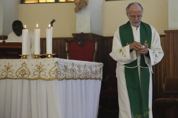 FILE - In this Sunday, June 30, 2019 file photo, The Rev. Mario Lacchin presides over a Mass at the Restoration Centre Catholic Church in Nairobi, Kenya. An Associated Press story on the front page of a newspaper in Nairobi brought together two Kenyan men - one who knew that his father was an Italian missionary priest, and the other who wanted proof that he was the son of the same priest. (AP Photo/Brian Inganga, File)