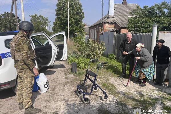 In this photo provided by the Ukrainian Police, police evacuate elderly people following the Russian attack around the town of Vovchansk in Kharkiv region, Ukraine, Friday, May 10, 2024. (Ukrainian Police via AP)