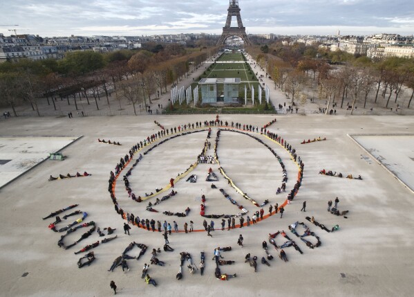 FILE - In this Dec. 6, 2015 file photo, environmental activists form a human chain representing the peace sign and spelling out "100% renewable", on the side lines of the COP21 United Nations climate change conference, near the Eiffel Tower in Paris.  (AP PhotoMichelle Euler, File)