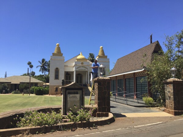 In this photo provided by Rev. Ai Hironaka, of the Lahaina Hongwanji Mission, a worker is fixing a lantern at the front of the property on March 31, 2017, in Lahaina, Hawaii. The temple was among the buildings that burned in a deadly wildfire in August 2023. Authorities on Monday, Sept. 25, 2023, will begin escorting the first residents back into the burn zone. (Ai Hironaka via AP)