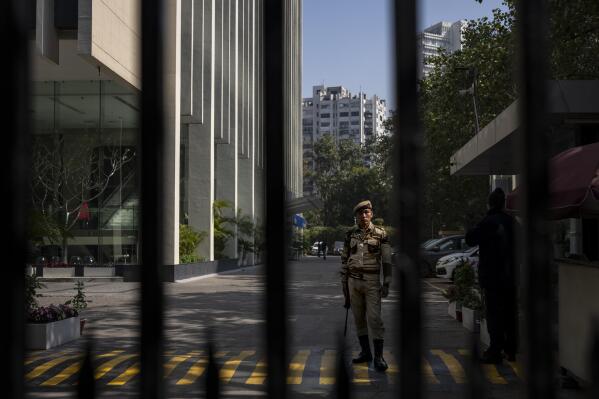 An armed security person stands stand guard at the gate of a building housing BBC office in New Delhi, India, Wednesday, Feb. 15, 2023. India’s tax officials searched BBC offices in India for a second straight day on Wednesday questioning the staff about the organization's business operations in the country, staff members said. (AP Photo/Altaf Qadri)