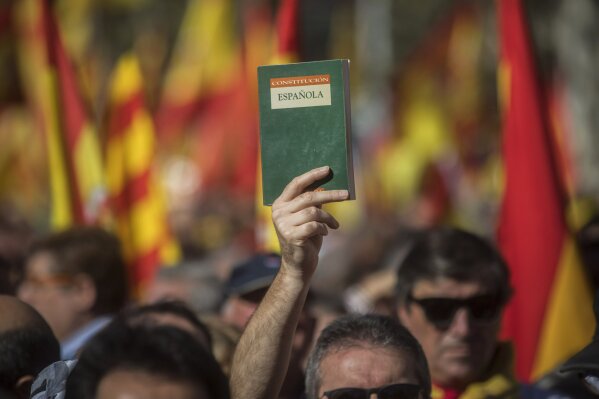 
              A demonstrator holds up a copy of the Spanish Constitution during a mass rally against Catalonia's declaration of independence, in Barcelona, Spain, Sunday, Oct. 29, 2017. Thousands of opponents of independence for Catalonia held the rally on one of the city's main avenues after one of the country's most tumultuous days in decades. (AP Photo/Santi Palacios)
            