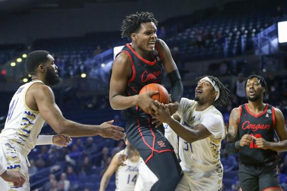 Houston's Josh Carlton brings down a rebound against Tulsa's Jeriah Horne, left, and LaDavius Draine during the first half of an NCAA college basketball game in Tulsa, Okla. on Saturday, Jan. 15, 2022. Houston's J'Wan Roberts is at far right. (AP Photo/Dave Crenshaw)