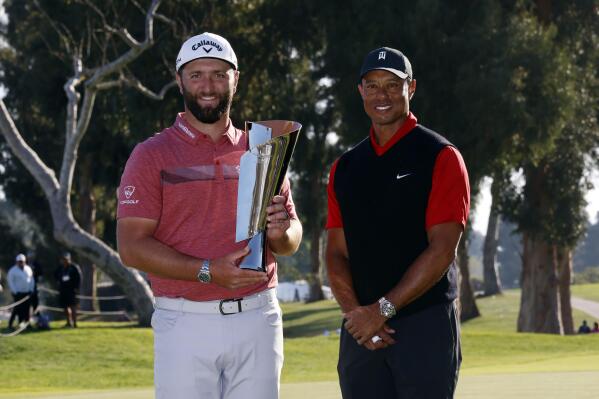 Jon Rahm, left, holds the winner's trophy next to Tiger Woods after winning the Genesis Invitational golf tournament at Riviera Country Club, Sunday, Feb. 19, 2023, in the Pacific Palisades area of Los Angeles. (AP Photo/Ryan Kang)