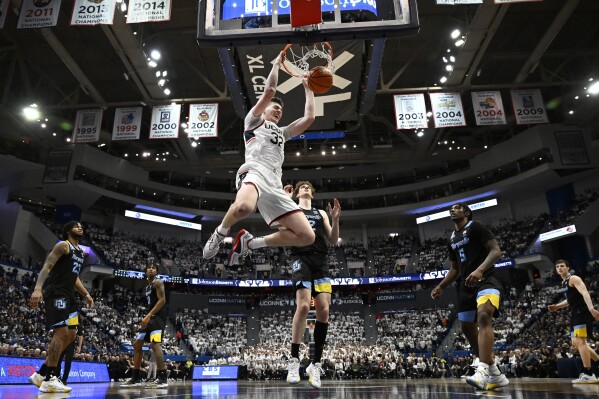 UConn center Donovan Clingan (32) dunks the ball in the second half of an NCAA college basketball game against Marquette, Saturday, Feb. 17, 2024, in Hartford, Conn. (AP Photo/Jessica Hill)