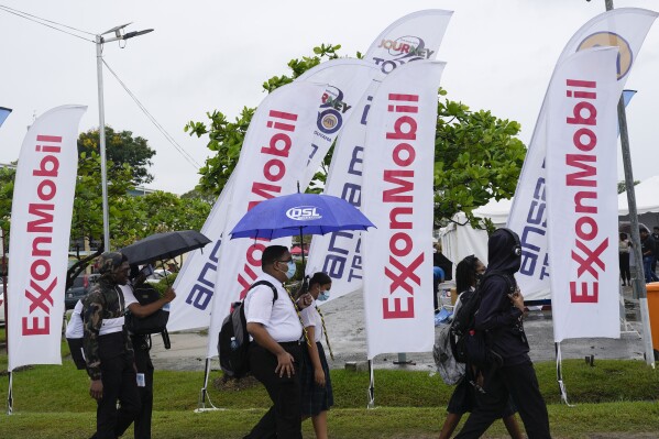 FILE - High school students walk past ExxonMobil flags as they arrive to a job fair at the University of Guyana in Georgetown, Guyana, April 21, 2023. ExxonMobil said on Feb. 7, 2024 that it plans to explore for oil and gas in the Essequibo, a region disputed between Guyana and Venezuela. Guyana awarded the exploration license. (AP Photo/Matias Delacroix, File)
