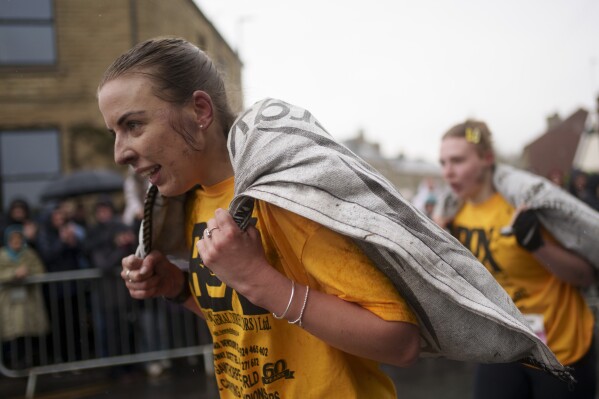 Women's race contestants make their way to the finish line, each carrying a 20kg sack of coal, at the World Coal Carrying Championships in Ossett, West Yorkshire, England, on Monday, April 21, 2025. (AP Photo/Jon Super)