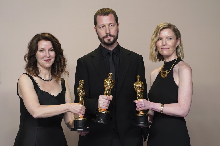 Raney Aronson-Rath, from left, Mstyslav Chernov, and Michelle Mizner pose in the press room with the award for best documentary feature film for 