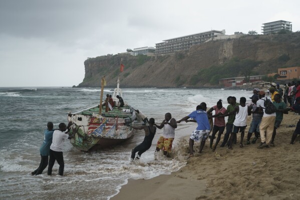 People work together to pull, according to the locals, the capsized boat ashore at the beach where several people were found dead in Dakar, Senegal, Monday, July 24, 2023. The bodies were discovered by the navy early in the morning and are believed to be migrants because of the type of boat they were in according to the authorities. (AP Photo/Leo Correa)