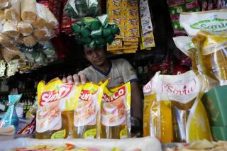 A vendor shows packs of cooking oil at his stall at a market in Jakarta, Indonesia, Sunday, April 17, 2022. Indonesia will ban exports of cooking oil and its raw materials to reduce domestic shortages and hold down prices, President Joko Widodo announced Friday, April 22, 2022. (AP Photo/Achmad Ibrahim)