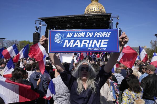 A woman holds a poster reading "in the name of the people - Marine president" during the French far-right party national rally near the parliament in support of Marine Le Pen in Paris, Sunday, April 6, 2025. (AP Photo/Michel Euler)