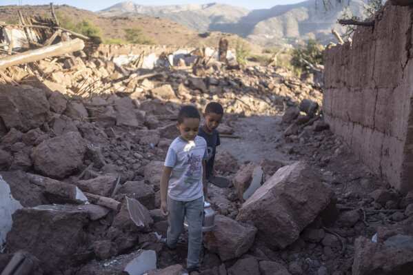 Moroccan boys, Rayan and Ali walk amidst the rubble of their home which was damaged by the earthquake, in Ijjoukak village, near Marrakech, Morocco, Saturday, Sept. 9, 2023. A rare, powerful earthquake struck Morocco, sending people racing from their beds into the streets and toppling buildings in mountainous villages and ancient cities not built to withstand such force. (AP Photo/Mosa'ab Elshamy)