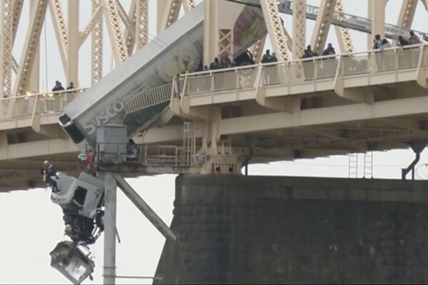Louisville emergency crews rescue the driver of semitruck that is dangling off the Clark Memorial Bridge over the Ohio River on Friday, March 1, 2024 in Louisville, Ky. The driver was pulled to safety by firefighters following the three-vehicle crash on the bridge connecting Louisville, Kentucky to southern Indiana. (WDRB via AP)