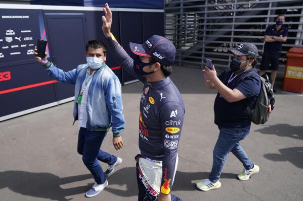 Red Bull driver Sergio Perez, of Mexico, greets fans from outside the paddock during the Formula One Mexico Grand Prix auto race at the Hermanos Rodriguez racetrack in Mexico City, Sunday, Nov. 7, 2021. (AP Photo/Eduardo Verdugo)