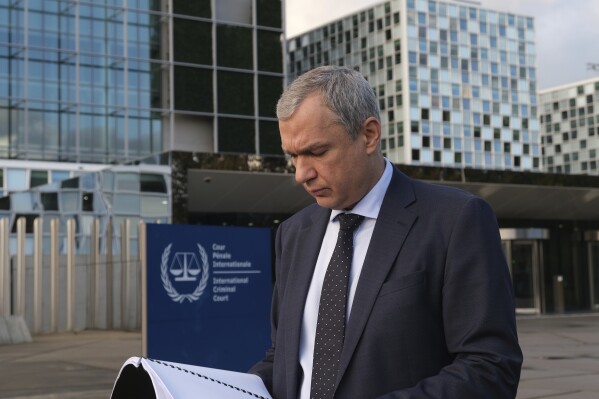 Exiled Belarus opposition activist Pavel Latushka reads from a file after he presented evidence to the International Criminal Court's prosecution office alleging the personal involvement of Belarus President Alexander Lukashenko in the illegal transfer of children to Belarus from Russian-occupied towns in Ukraine, outside the ICC in The Hague, Netherlands, Tuesday, Nov. 7, 2023. (AP Photo/Mike Corder)