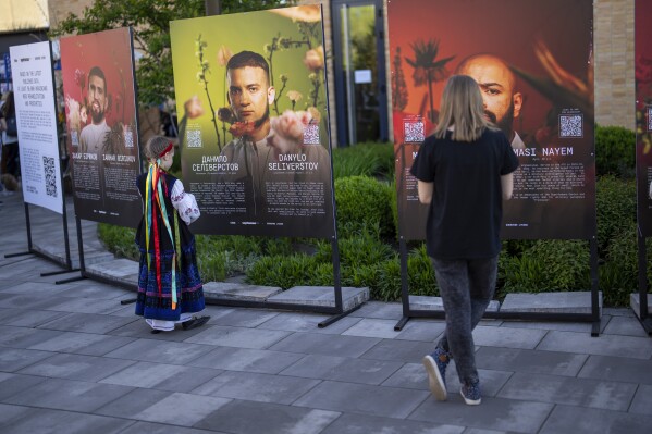 People look at boards displaying photographs of Ukrainian soldiers who have suffered amputations and severe injures during the war, in Kyiv, Ukraine, Sunday, April 28, 2024. (AP Photo/Francisco Seco)