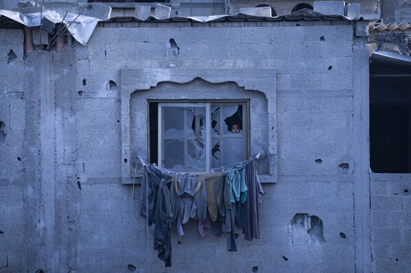 A child looks through a broken window in Rafah, Gaza Strip, Wednesday, Feb. 21, 2024. An estimated 1.5 million Palestinians displaced by the war took refuge in Rafahor, which is likely Israel's next focus in its war against Hamas. (AP Photo/Fatima Shbair)