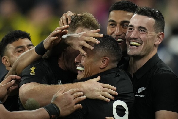 New Zealand's Aaron Smith, center, is congratulated by teammates after scoring a try during the Rugby World Cup semifinal match between Argentina and New Zealand at the Stade de France in Saint-Denis, outside Paris, Friday, Oct 20, 2023. (AP Photo/Christophe Ena)